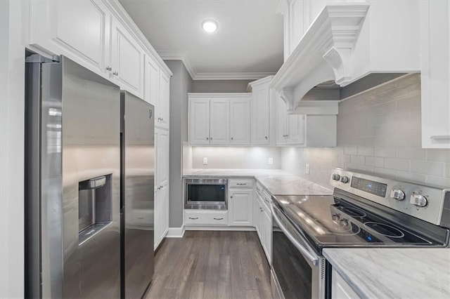 kitchen with appliances with stainless steel finishes, white cabinets, crown molding, dark wood finished floors, and backsplash
