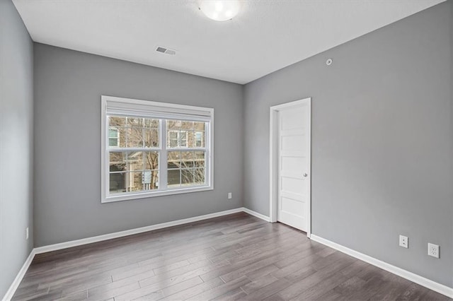 empty room with dark wood finished floors and baseboards