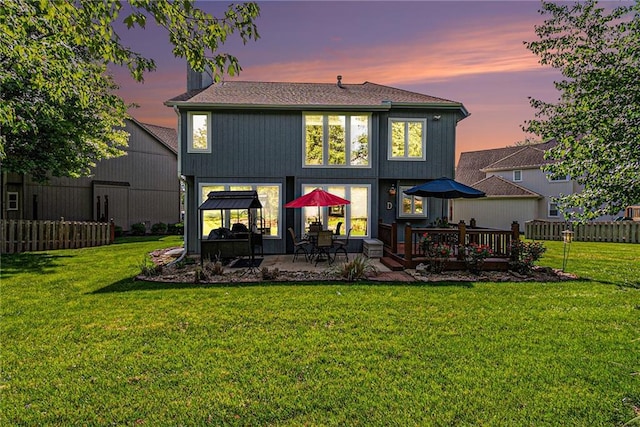 back of property at dusk featuring a wooden deck and a patio