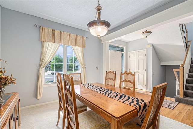 dining area featuring stairs, a textured ceiling, and baseboards