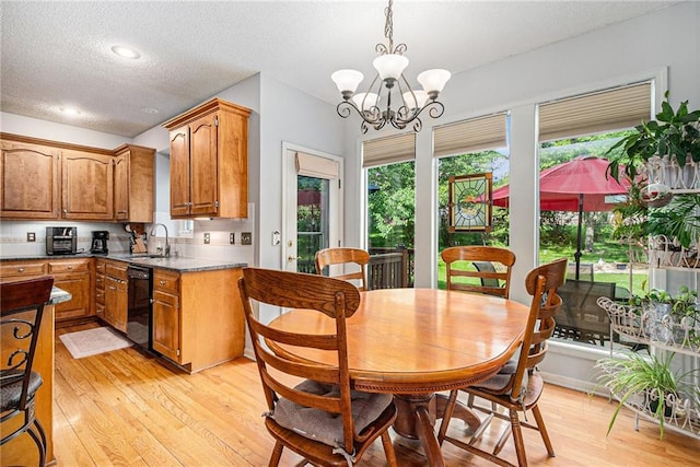 dining room with light wood finished floors, a chandelier, and a textured ceiling