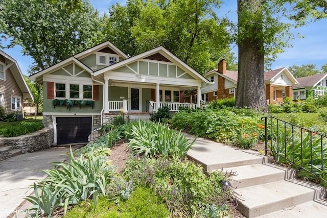 5825 Rockhill Rd, Kansas City, MO 64110 - craftsman house featuring a porch, stone siding, concrete driveway, a garage, and stucco siding