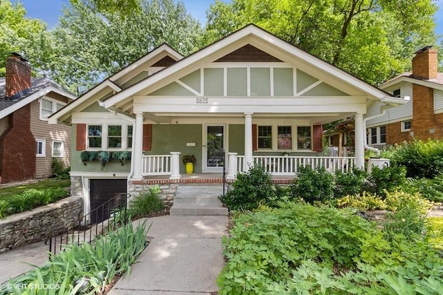 5825 Rockhill Rd, Kansas City, MO 64110 - view of front facade with covered porch, a garage, and stucco siding