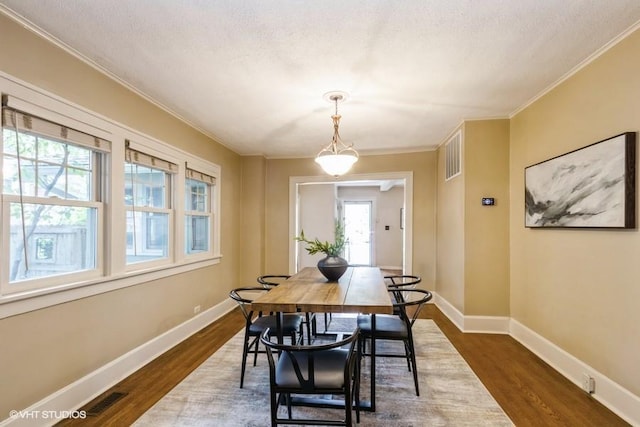 5825 Rockhill Rd, Kansas City, MO 64110 - dining area featuring dark wood finished floors, ornamental molding, and baseboards
