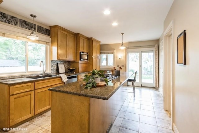 5825 Rockhill Rd, Kansas City, MO 64110 - kitchen featuring appliances with stainless steel finishes, light tile patterned floors, dark stone counters, a kitchen island, and recessed lighting