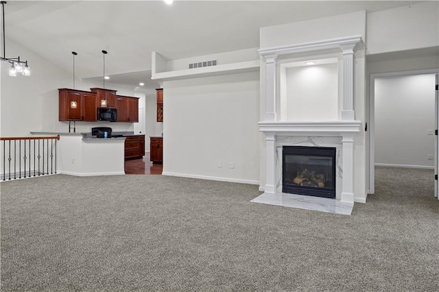 unfurnished living room with carpet, lofted ceiling, a high end fireplace, visible vents, and baseboards