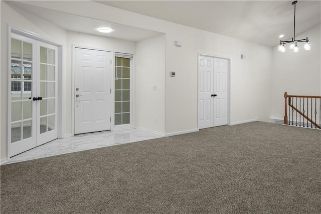 foyer entrance with a chandelier, carpet floors, and baseboards
