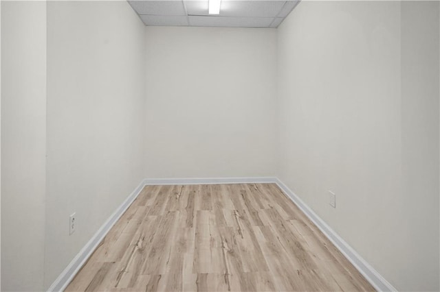 spare room featuring baseboards, wood finished floors, and a drop ceiling