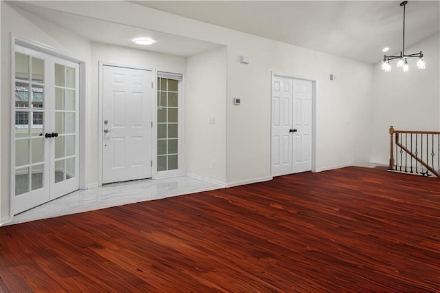 foyer with wood finished floors, baseboards, and an inviting chandelier