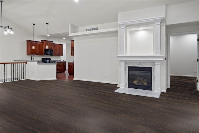 unfurnished living room featuring a high end fireplace, baseboards, dark wood-style flooring, visible vents, and recessed lighting