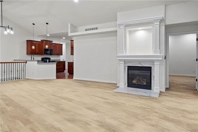 unfurnished living room with light wood-type flooring, baseboards, visible vents, recessed lighting, and a high end fireplace