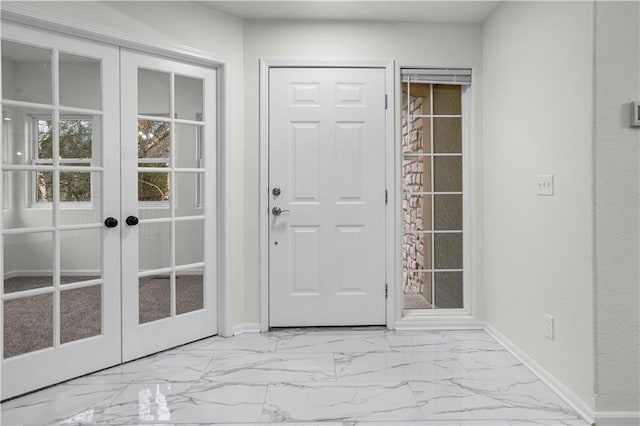 doorway to outside featuring marble finish floor, baseboards, and french doors
