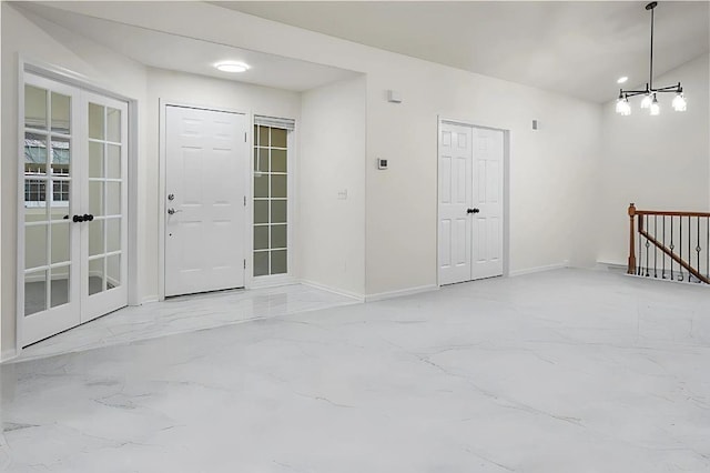 foyer entrance with marble finish floor, baseboards, and an inviting chandelier
