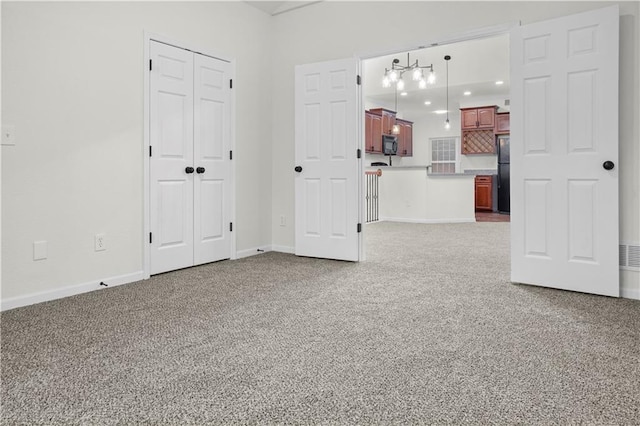 unfurnished bedroom featuring baseboards, freestanding refrigerator, carpet floors, and a closet