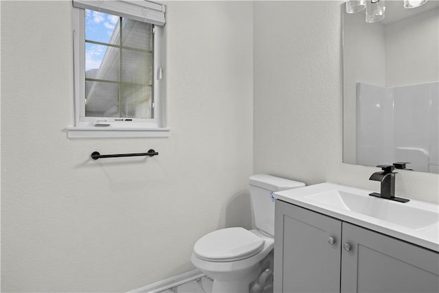 bathroom with marble finish floor, toilet, a textured wall, and vanity