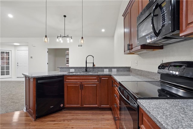 kitchen featuring a sink, decorative light fixtures, light stone countertops, black appliances, and a peninsula