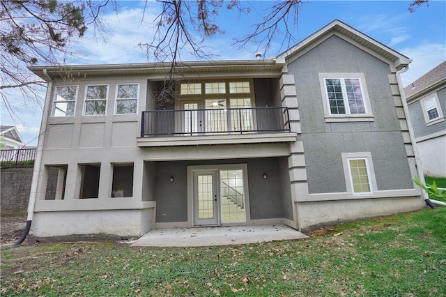 rear view of house featuring a balcony, a yard, stucco siding, a patio area, and french doors