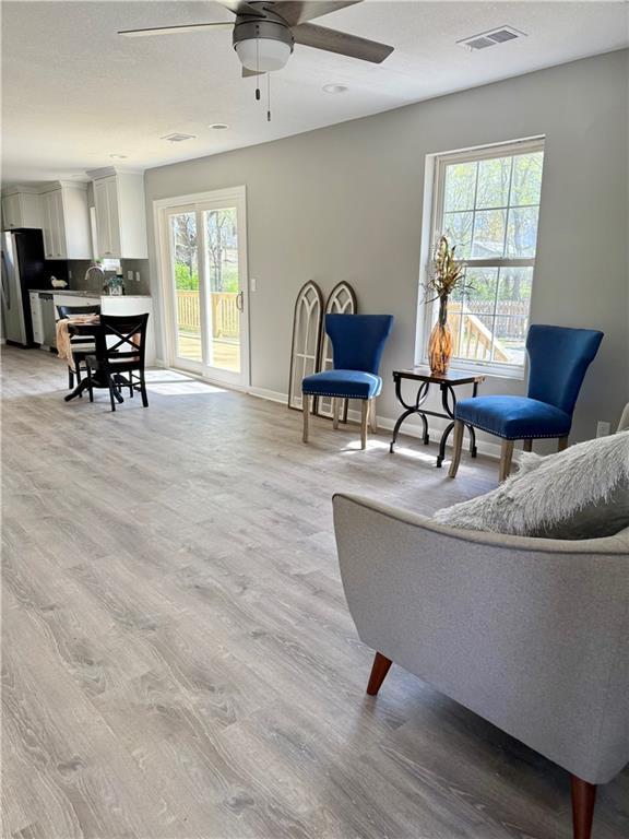 112 Benton St, Pleasant Hill, MO 64080 - sitting room featuring light wood-type flooring, a healthy amount of sunlight, a ceiling fan, and visible vents