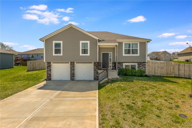 raised ranch with concrete driveway, a garage, fence, and stone siding