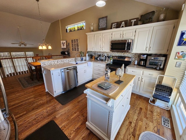 5773 Meadow Heights Dr, Shawnee, KS 66226 - kitchen with stainless steel appliances, lofted ceiling, a peninsula, white cabinetry, and decorative backsplash