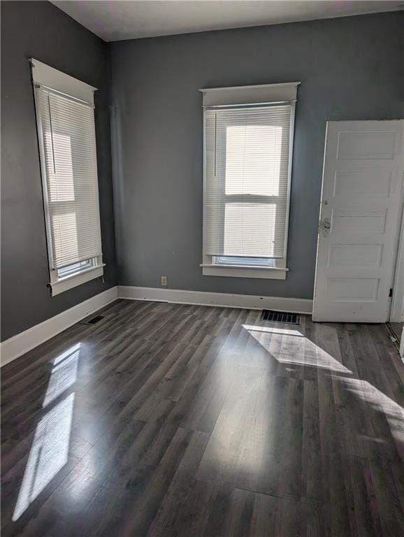 unfurnished room with baseboards, wood finished floors, and visible vents