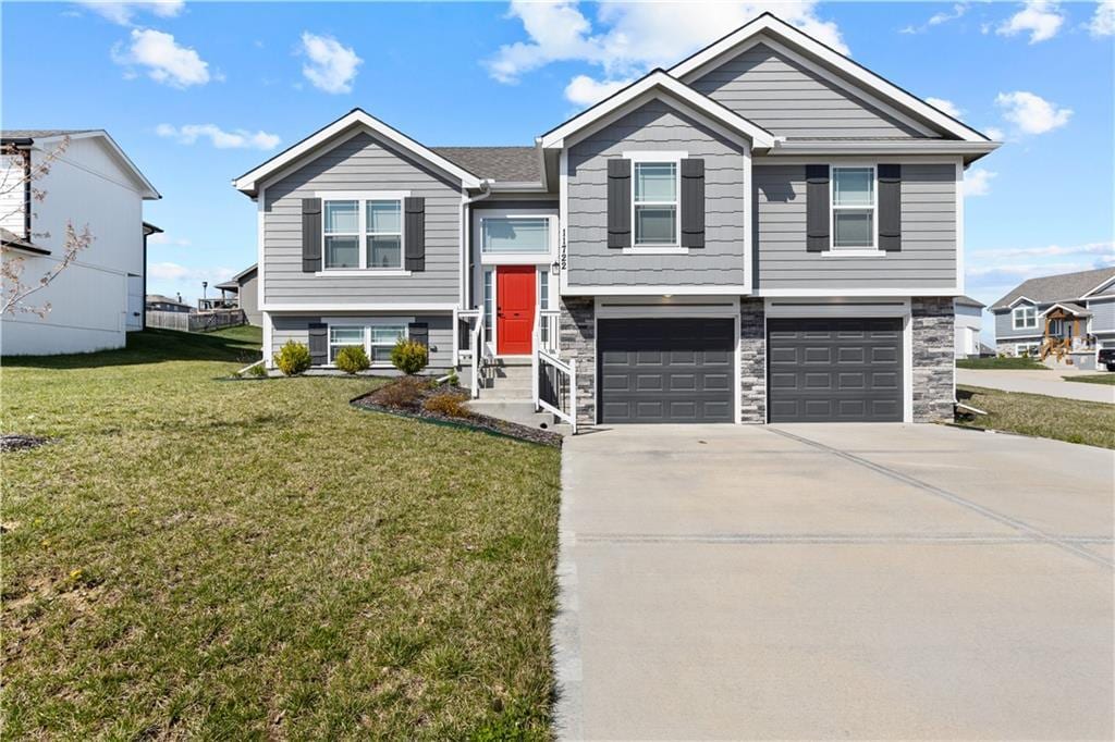 11722 N Windsor Ave, Kansas City, MO 64157 - split foyer home featuring a garage, concrete driveway, stone siding, and a front lawn