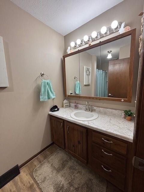 bathroom featuring baseboards, wood finished floors, vanity, and a textured ceiling