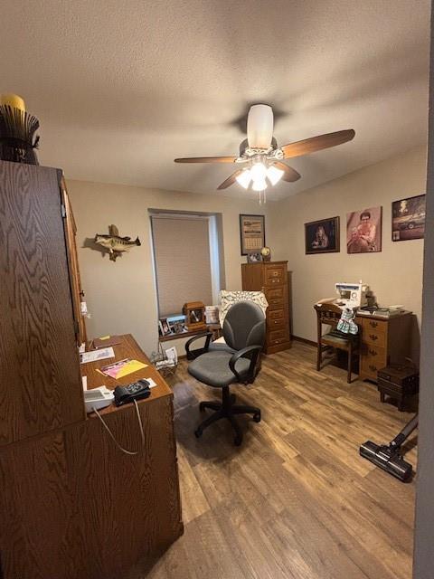 home office with a ceiling fan, a textured ceiling, and wood finished floors