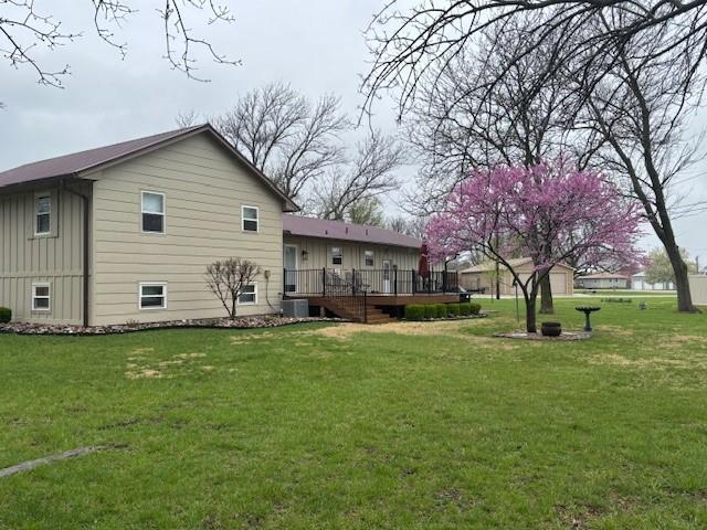back of house with a deck, board and batten siding, and a yard