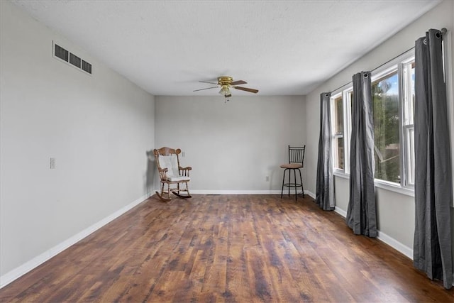 empty room featuring visible vents, baseboards, a ceiling fan, and wood finished floors