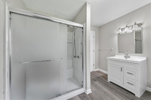 bathroom with a stall shower, wood finished floors, vanity, and a textured ceiling