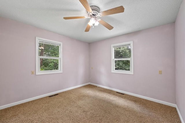 unfurnished room featuring carpet flooring, baseboards, visible vents, and a wealth of natural light