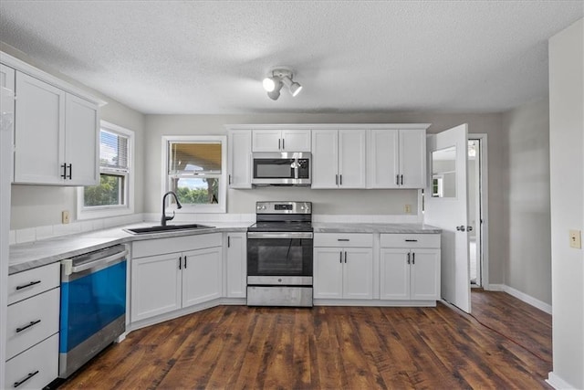 kitchen featuring stainless steel appliances, white cabinets, light countertops, and a sink