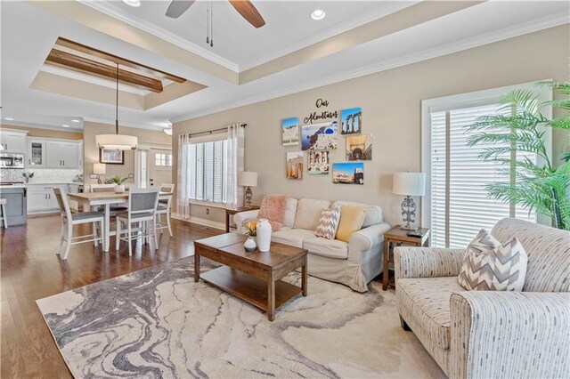 11481 S Waterford Dr, Olathe, KS 66061 - living room featuring a healthy amount of sunlight, a raised ceiling, ornamental molding, and dark wood finished floors