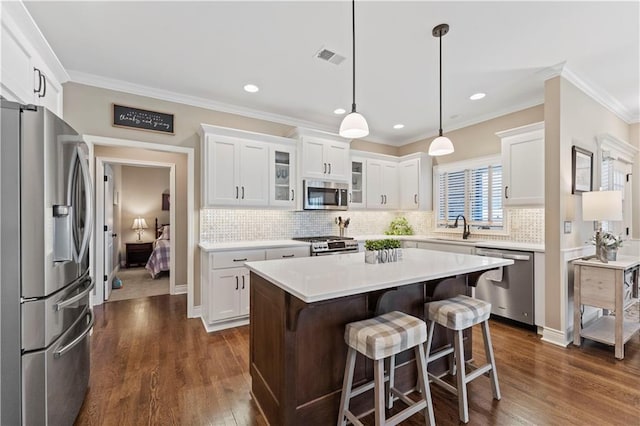 11481 S Waterford Dr, Olathe, KS 66061 - kitchen featuring a kitchen bar, light countertops, glass insert cabinets, stainless steel appliances, and white cabinetry