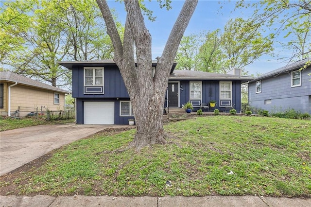 tri-level home with board and batten siding, fence, driveway, a front lawn, and an attached garage