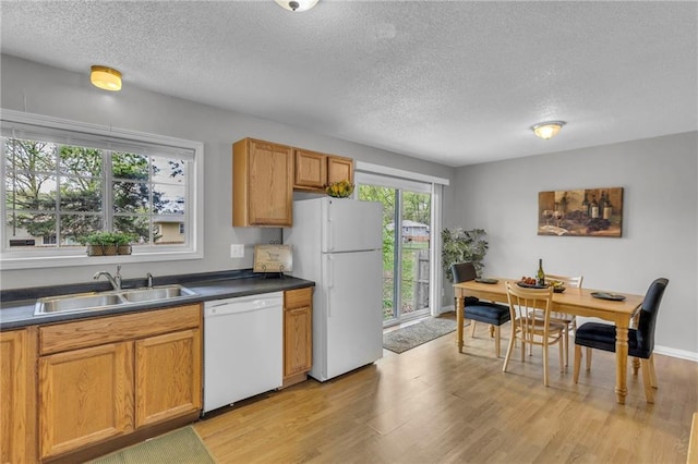 kitchen with white appliances, a textured ceiling, light wood finished floors, and a sink