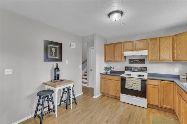 kitchen with visible vents, range with electric cooktop, light wood-style floors, and under cabinet range hood