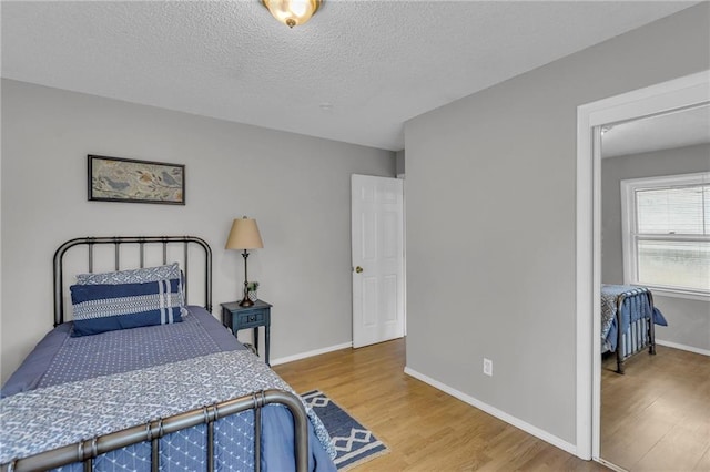 bedroom featuring baseboards, wood finished floors, and a textured ceiling