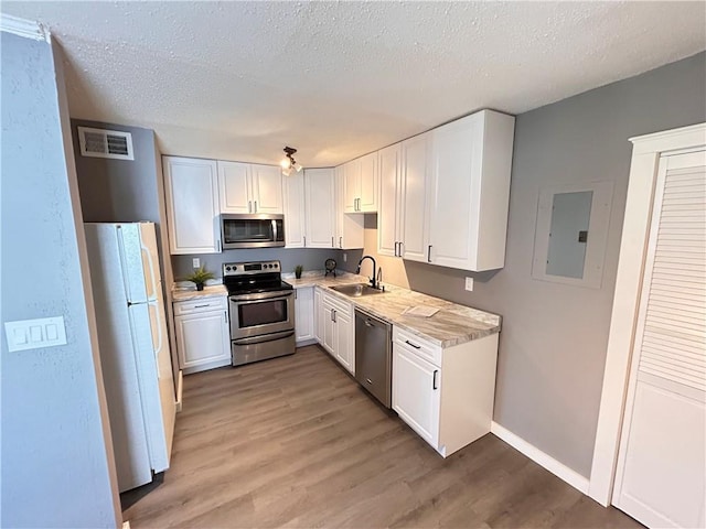 7940 Hickman Mills Dr, Kansas City, MO 64132 - kitchen featuring electric panel, a sink, stainless steel appliances, visible vents, and light wood-style floors