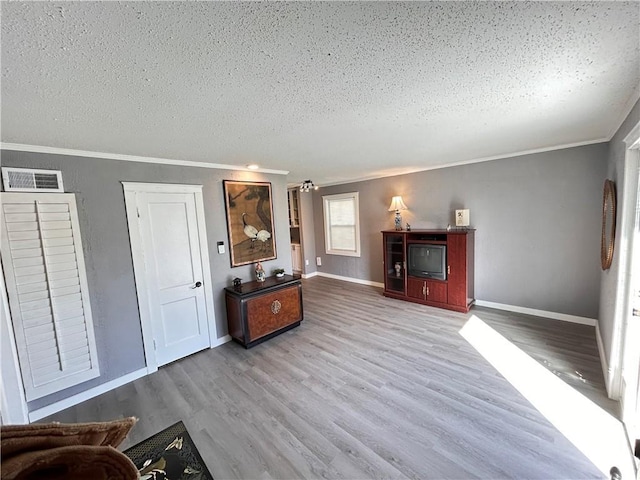 7940 Hickman Mills Dr, Kansas City, MO 64132 - unfurnished living room with crown molding, baseboards, a textured ceiling, visible vents, and wood finished floors