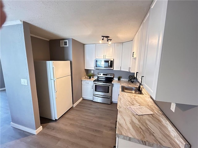 7940 Hickman Mills Dr, Kansas City, MO 64132 - kitchen with visible vents, white cabinets, a sink, and appliances with stainless steel finishes