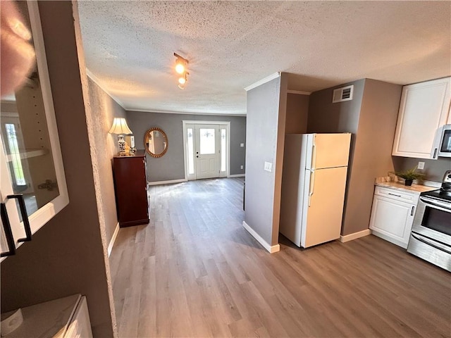 7940 Hickman Mills Dr, Kansas City, MO 64132 - kitchen featuring white cabinetry, appliances with stainless steel finishes, a textured ceiling, light wood-type flooring, and visible vents