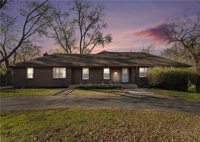single story home with aphalt driveway, a yard, and brick siding