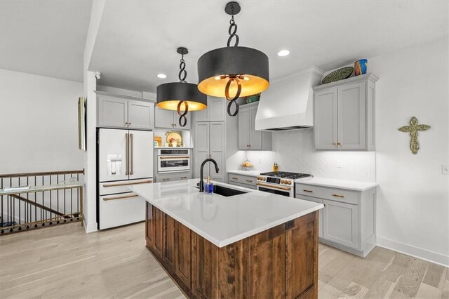 2428 W 179th St, Overland Park, KS 66085 - kitchen with premium appliances, a sink, custom range hood, light wood-style flooring, and light countertops