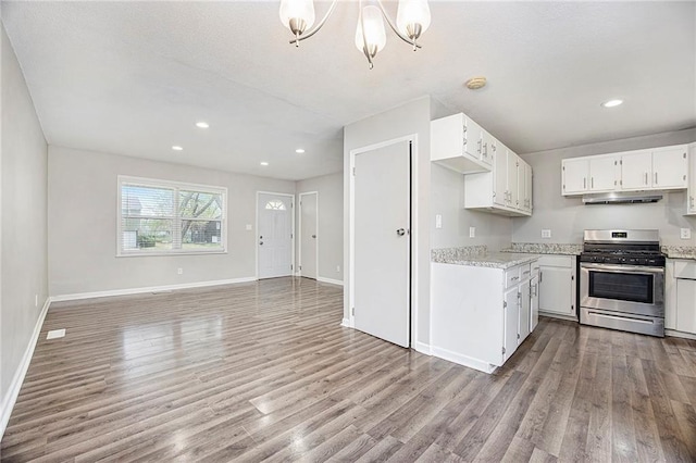 kitchen with white cabinets, light wood-style flooring, baseboards, stainless steel gas stove, and an inviting chandelier