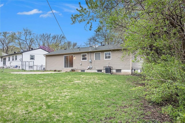 back of property featuring entry steps, central AC, fence, and a lawn