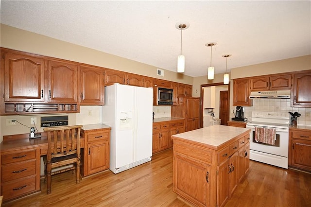 2406 NE 78th Ter, Kansas City, MO 64118 - kitchen with white appliances, under cabinet range hood, light wood-style flooring, and tasteful backsplash