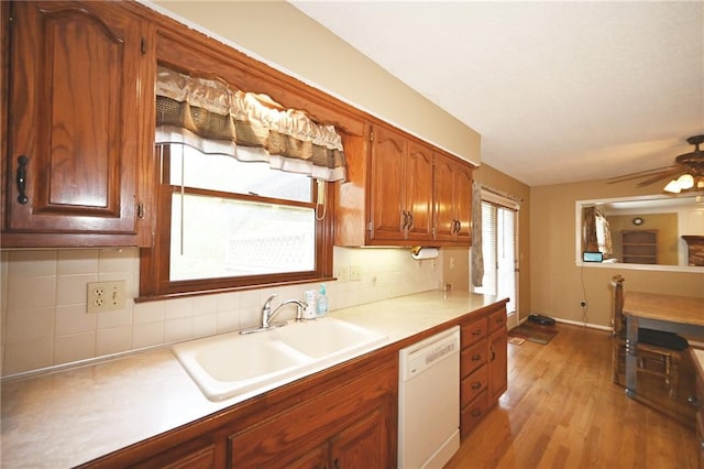 2406 NE 78th Ter, Kansas City, MO 64118 - kitchen featuring white dishwasher, a sink, light countertops, and tasteful backsplash