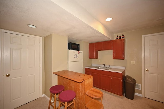 2406 NE 78th Ter, Kansas City, MO 64118 - kitchen with freestanding refrigerator, black microwave, light carpet, a sink, and baseboards